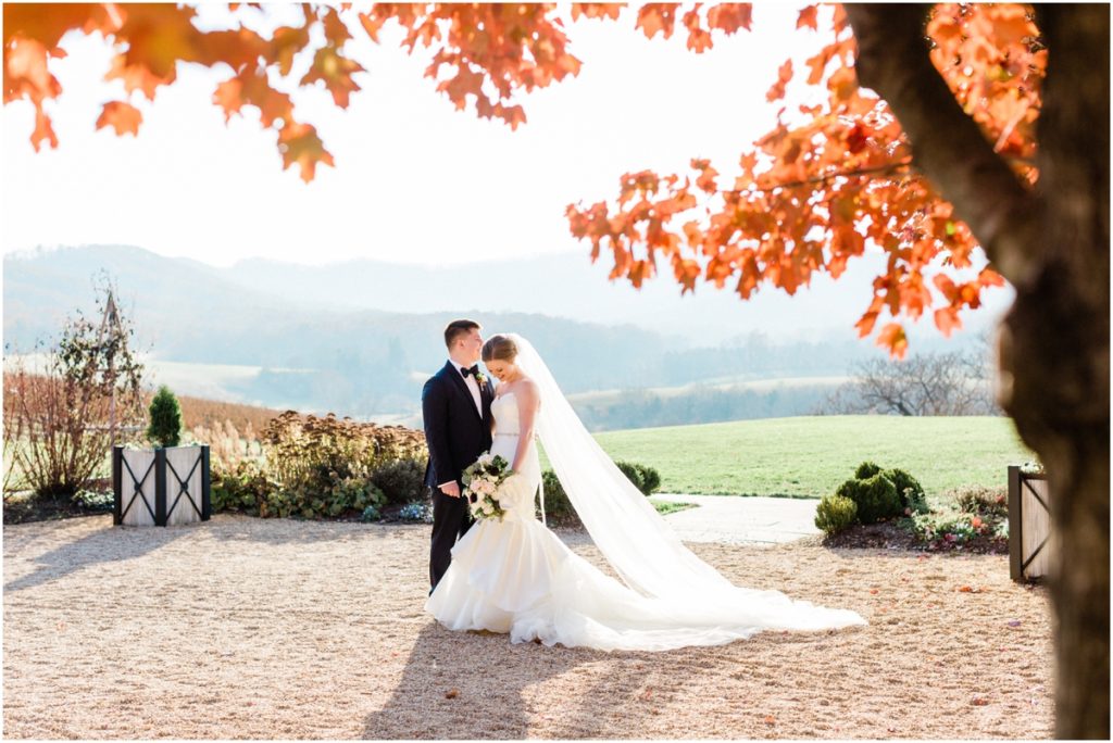 bride and groom laughing among fall leaves